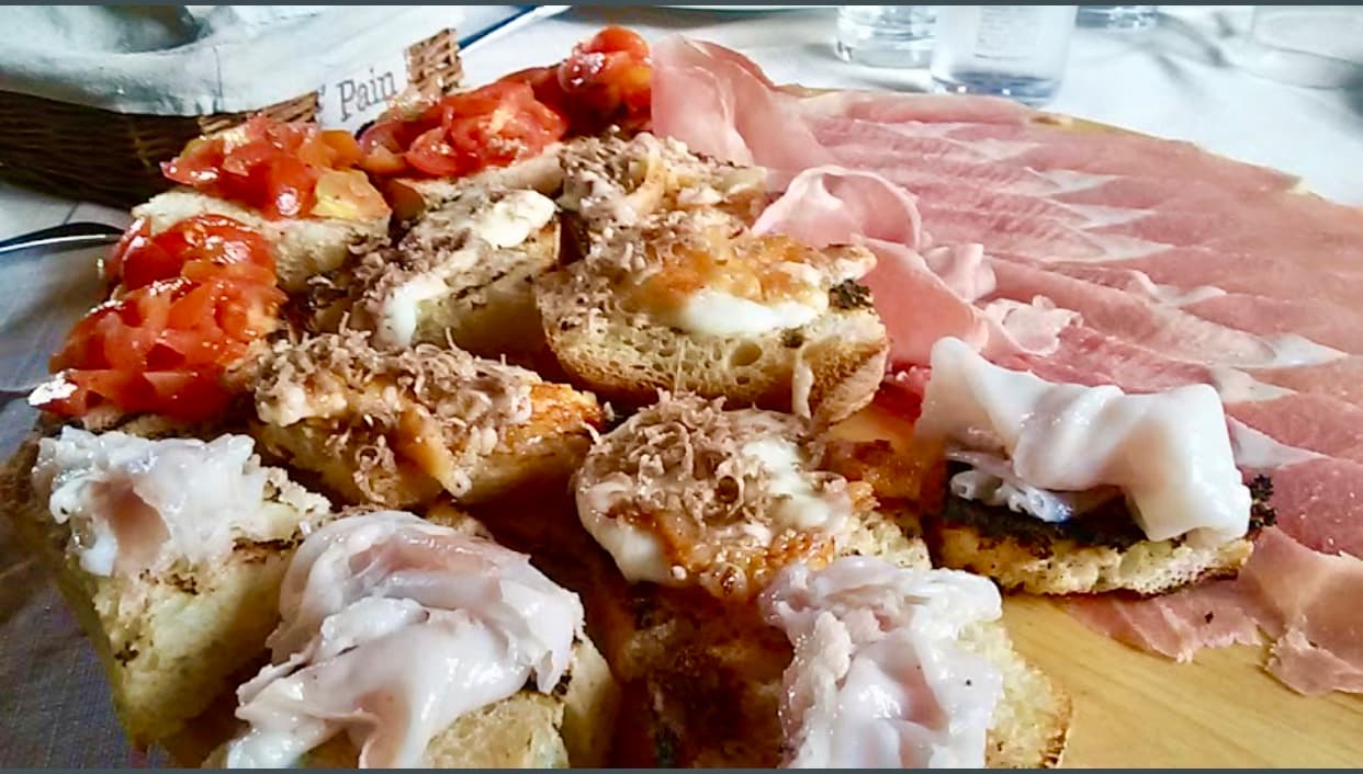Tagliere con crostini al tartufo, bruschette al pomodoro e affettati misti su tavola imbandita