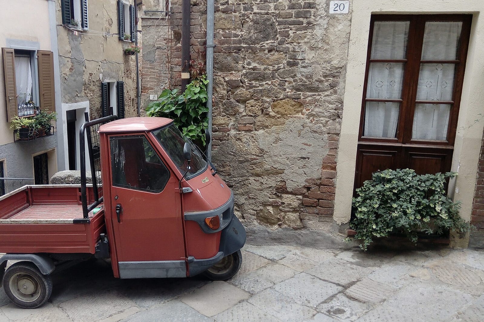 Une ruelle de Chianciano Vecchia avec un triporteur garé et des maisons en pierre