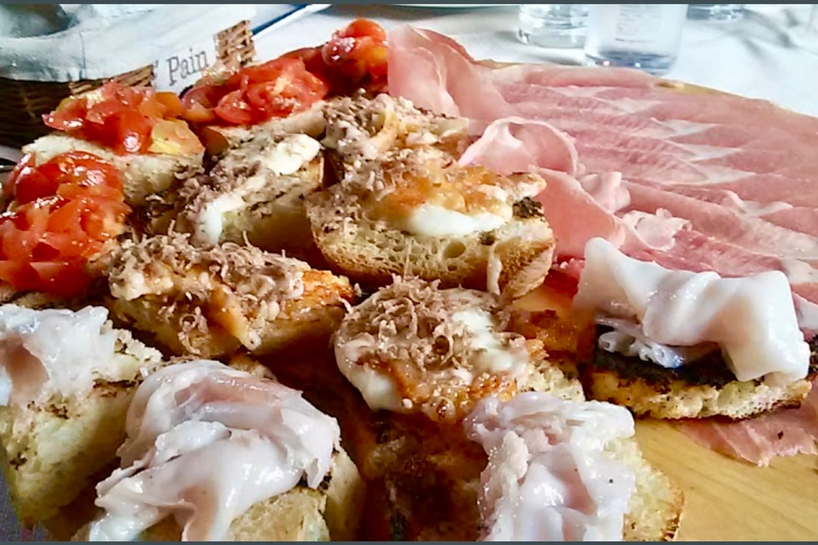 Crostini with grated truffle and cured meats served on a plate