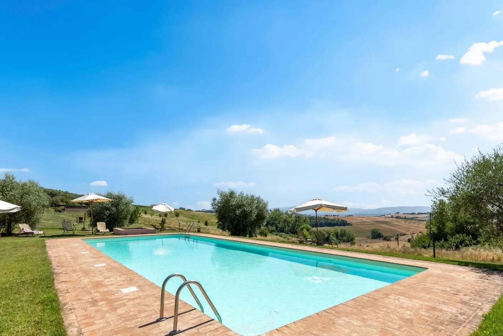 The outdoor pool with its terracotta surround and the hills behind it on a sunny day