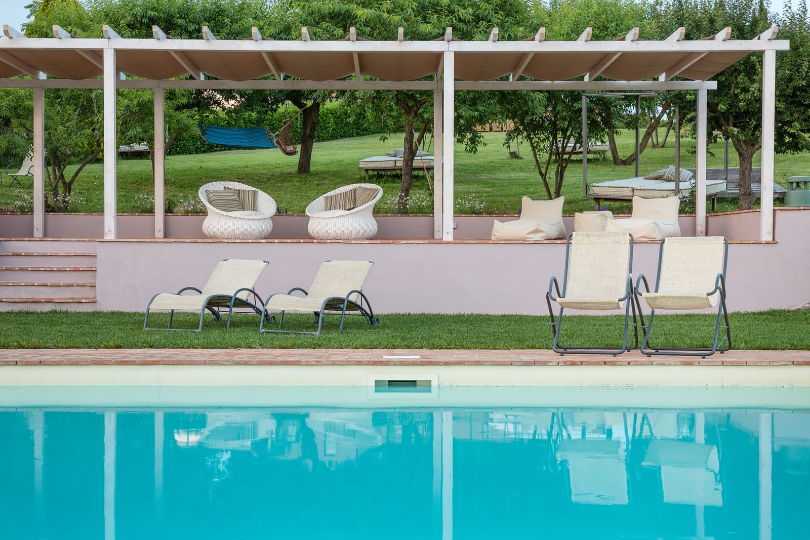 The pergola beside the outdoor pool, with loungers and armchairs in the shade