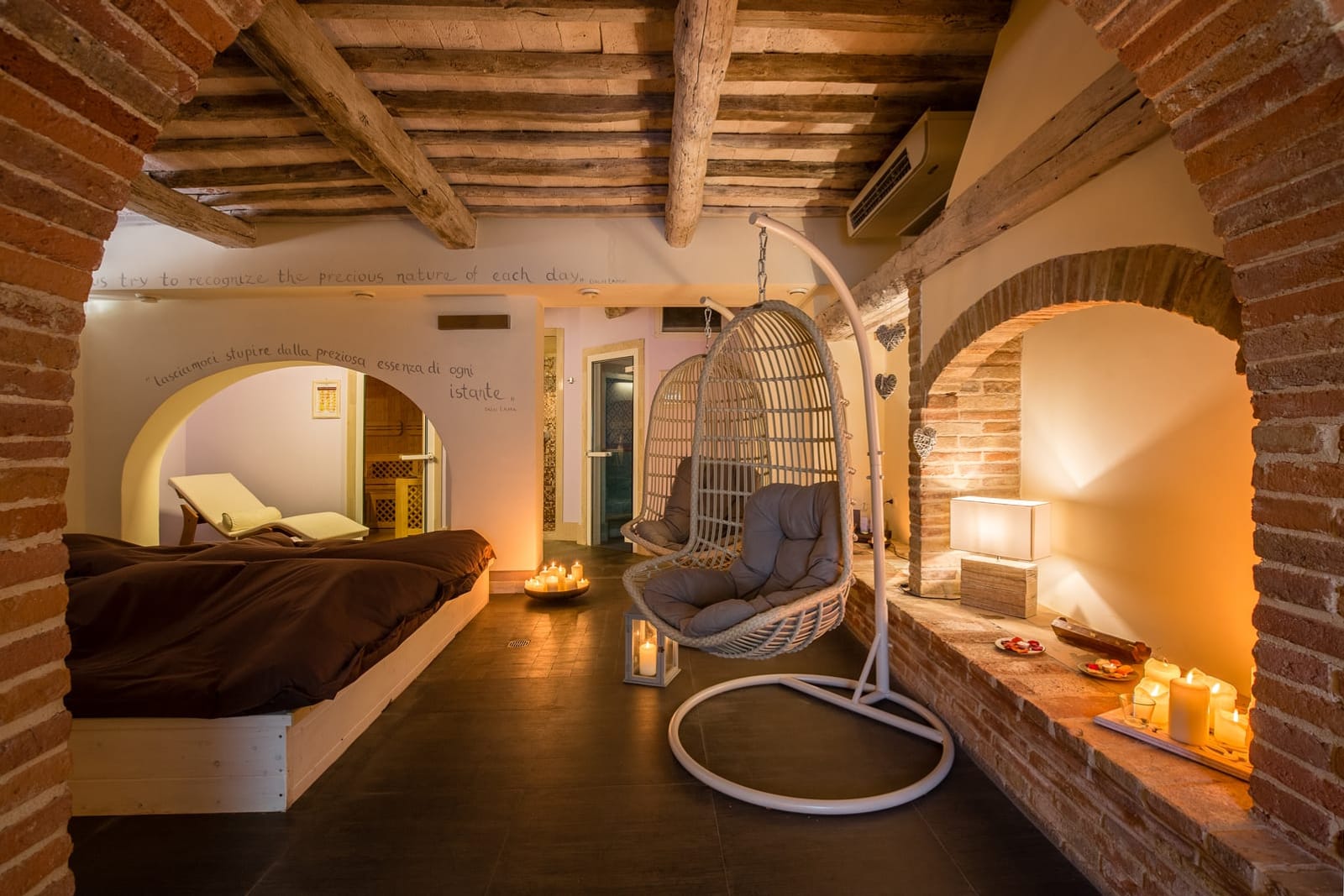 The relaxation room under its brick vaults, with the hanging chair and lit candles