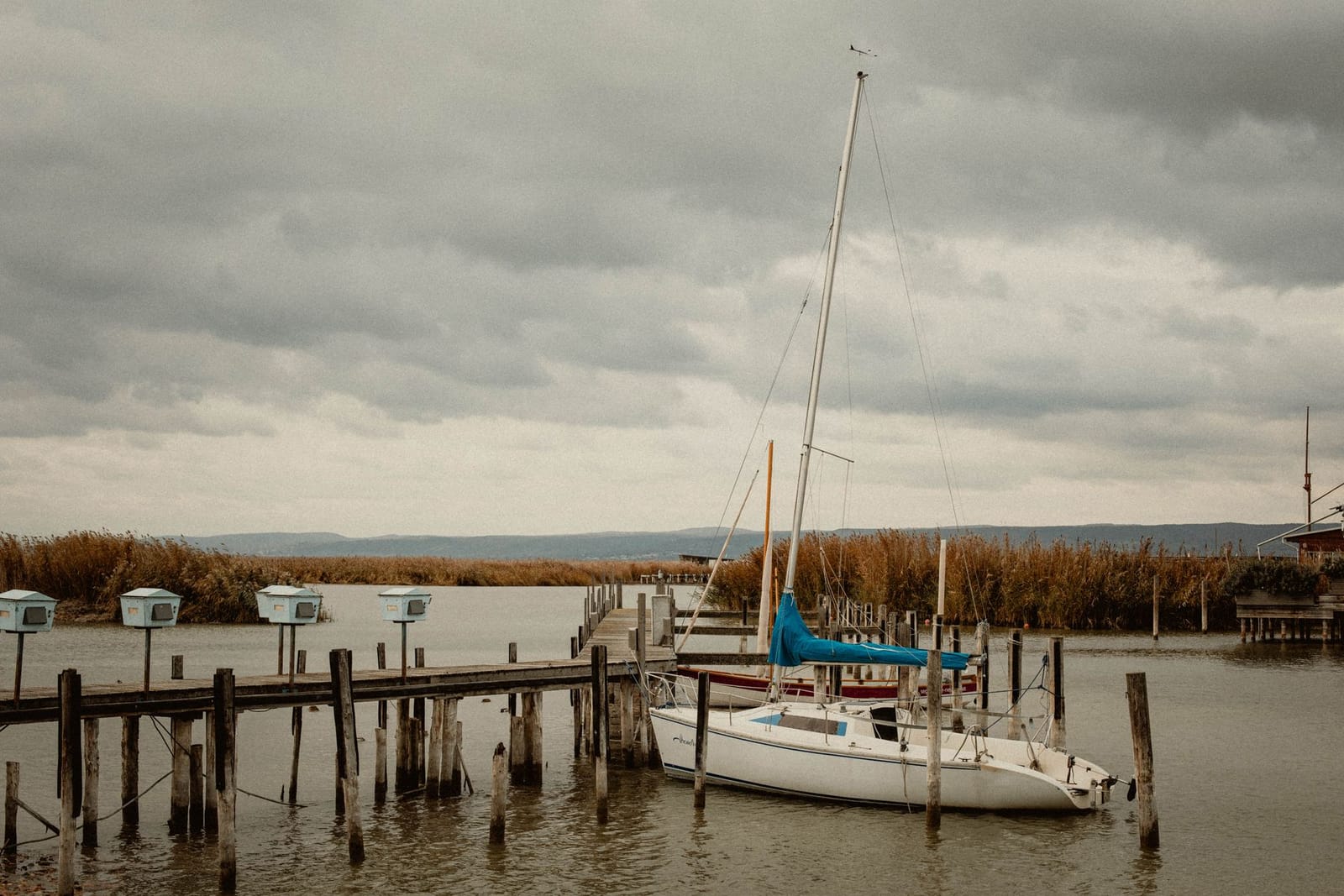 A wooden jetty on Lake Trasimeno with a sailing boat moored