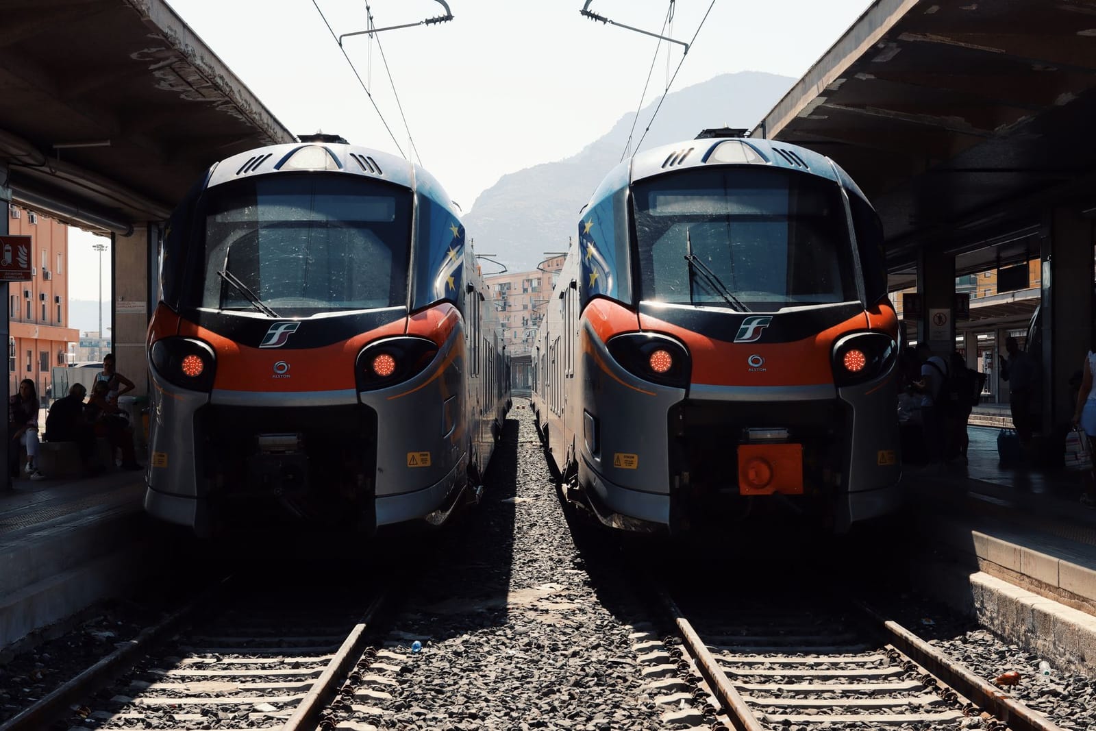 Dos trenes regionales parados uno al lado del otro en las vías de una estación italiana